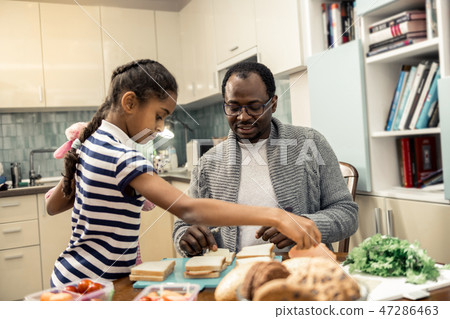 Helpful daughter with nice hairstyle helping father in kitchen Helpful daughter with nice hairstyle helping father in kitchen 47286463
