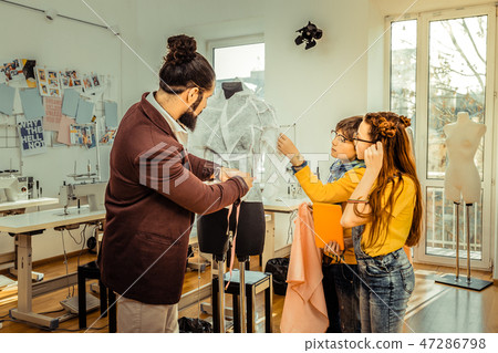 Bearded fashion designer showing his work process to children Bearded fashion designer showing his work process to children 47286798