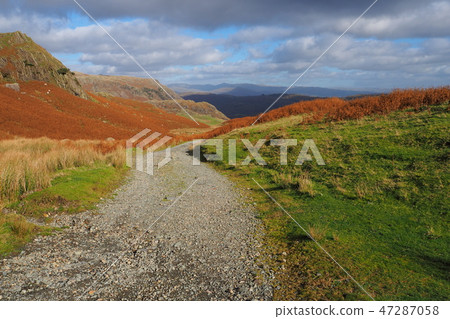Path over the mountains through heather and bracken in warm Autumn colours, Lake District Path over the mountains through heather and bracken in warm Autumn colours, Lake District 47287058