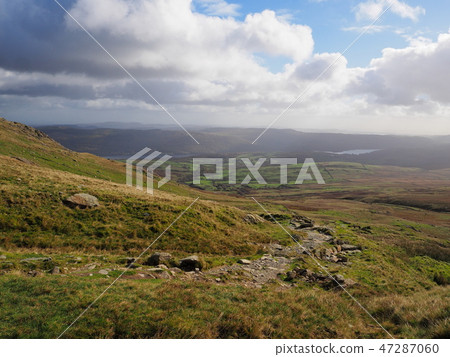 Path over the mountains with Coniston Water in the distance, with warm Autumn colours, Lake District Path over the mountains with Coniston Water in the distance, with warm Autumn colours, Lake District 47287060