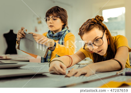 Future fashion designers using rulers while measuring fabrics 47287659