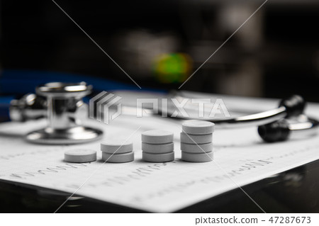 stethoscope and stairs from tablets lie on sheet with electrocardiogram 47287673