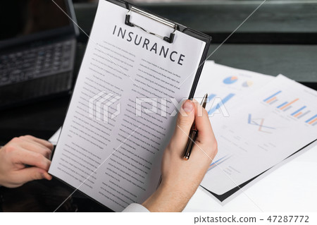 young man gets acquainted with terms of insurance in bright office 47287772