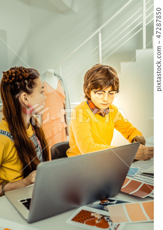 Brother and sister sitting in front of laptop getting ready for presentation 47287850