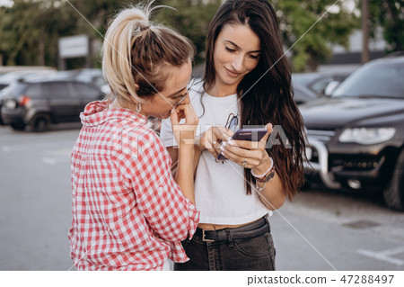 Two beautiful young women are looking at a smartphone 47288497