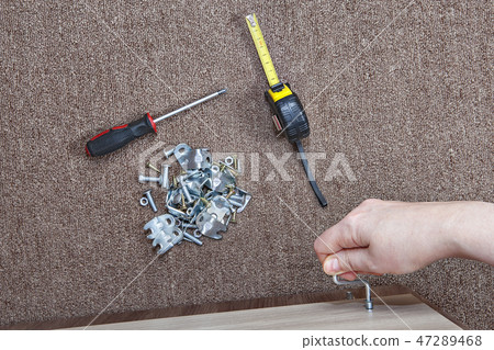 Human hand assembling wood furniture using hex key 47289468