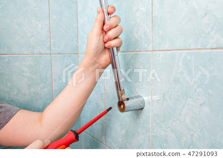 hands uninstalling broken vertical shower 47291093
