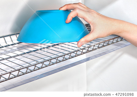 Hand takes bowl from kitchen cupboard  47291098