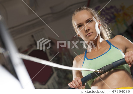 Sporty Blonde woman exercising on rowing machine Sporty Blonde woman exercising on rowing machine 47294089