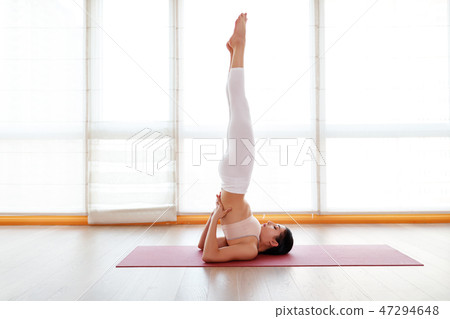 young woman practices yoga at  gym by window 47294648