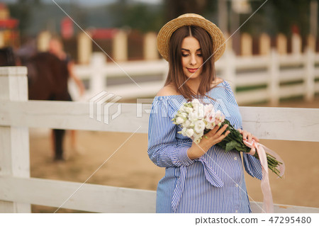 Georgeus woman stand in front of farm and hold a bouquet of flower in hands. Beautuful bouquet Georgeus woman stand in front of farm and hold a bouquet of flower in hands. Beautuful bouquet 47295480