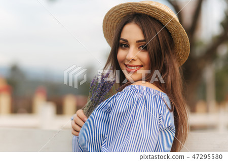 Portrait of young pregnant woman near the farm. Close up view of lady in hat with lavender in hand Portrait of young pregnant woman near the farm. Close up view of lady in hat with lavender in hand 47295580