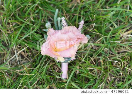 groom's peach eustoma boutonniere on green grass 47296081
