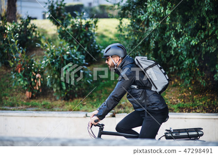 Male bicycle courier delivering packages in city. Copy space. Male bicycle courier delivering packages in city. Copy space. 47298491