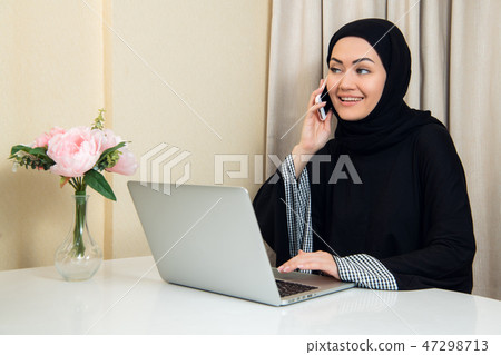 cheerful happy pretty muslim woman sitting and using mobile cell phone calling for friend chatting 47298713