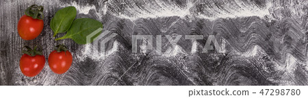 Black background with wheat flour spread on it. Tomato with basil leaves Black background with wheat flour spread on it. Tomato with basil leaves 47298780