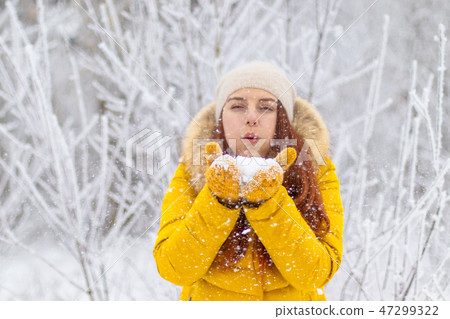 Happy girl in winter clothes blowing on palms 47299322