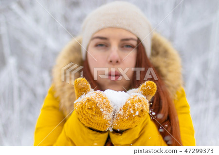Happy girl in winter clothes blowing on palms Happy girl in winter clothes blowing on palms 47299373