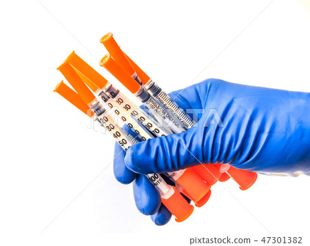 Doctor's hand in blue medical glove holding several syringes with medical solution white isolated Doctor's hand in blue medical glove holding several syringes with medical solution white isolated 47301382