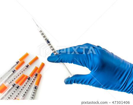 Doctor's hand in blue medical glove holding syringe with medical solution. Several empty syringes Doctor's hand in blue medical glove holding syringe with medical solution. Several empty syringes 47301406