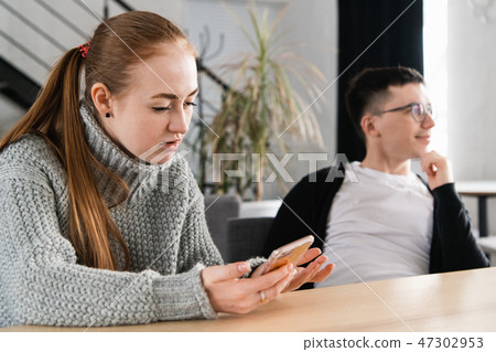 Woman reading her man's cheating messages on his phone Woman reading her man's cheating messages on his phone 47302953
