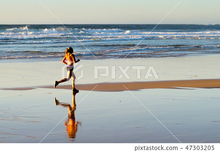 Woman jogging ocean beach sunset Woman jogging ocean beach sunset 47303205