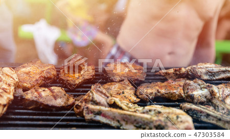 Friends frying the meat ribs and steaks, barbecue Friends frying the meat ribs and steaks, barbecue 47303584