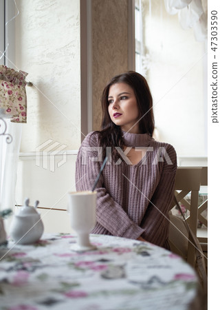 Young beautiful girl sitting at table in cafe Young beautiful girl sitting at table in cafe 47303590