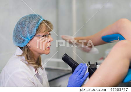 Professional gynecologist examining her female patient on a gynecological chair. 47303757