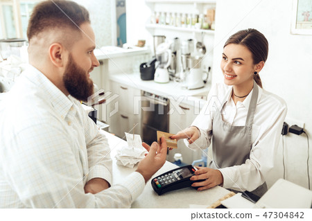 Cheerful cashier using digital device for payment Cheerful cashier using digital device for payment 47304842