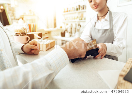 Cheerful cashier using digital device for payment Cheerful cashier using digital device for payment 47304925