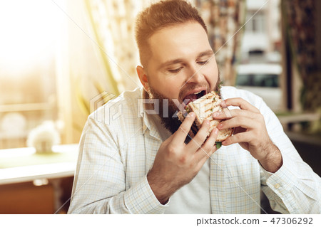Portrait of man eating in cafe and enjoying food Portrait of man eating in cafe and enjoying food 47306292