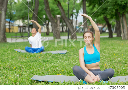 Young couple meditating on green grass 47308905
