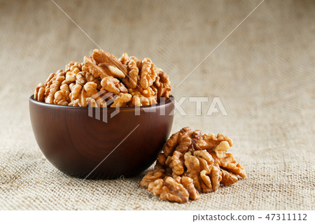 Peeled walnuts in a wooden, dark brown cup on Peeled walnuts in a wooden, dark brown cup on 47311112