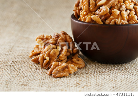 Peeled walnuts in a wooden, dark brown cup on Peeled walnuts in a wooden, dark brown cup on 47311113