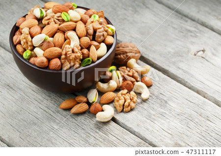 Wooden bowl with mixed nuts on a wooden gray 47311117