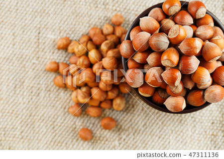 Peeled hazelnuts in a wooden, dark brown cup on Peeled hazelnuts in a wooden, dark brown cup on 47311136