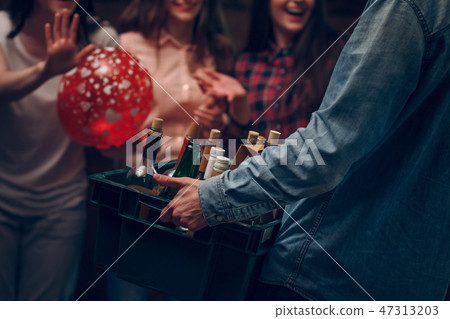Man holding box with bottles of champagne at a party Man holding box with bottles of champagne at a party 47313203