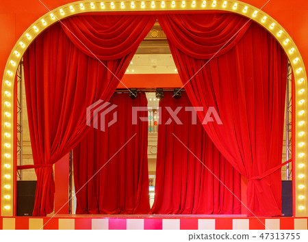 Theater stage with red curtains and spotlights. Theatrical scene in the light of searchlights, the 47313755