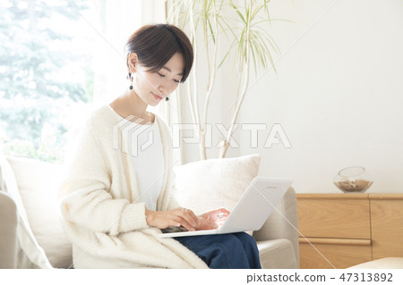 A woman who plays a personal computer in the living room A woman who plays a personal computer in the living room 47313892