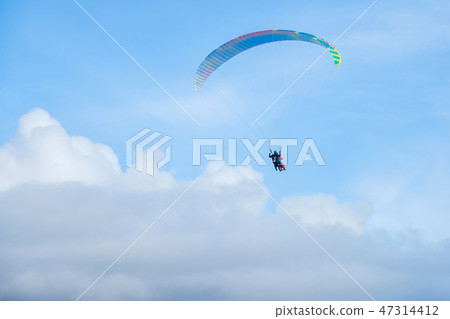 Paragliders in bright blue sky, tandem of instructor and beginner 47314412