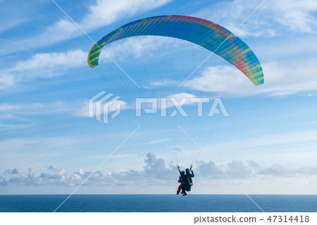 Flying a tandem paraglider over the sea with views of the horizon 47314418