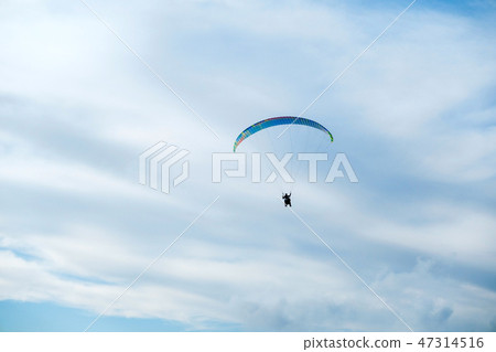 Paragliders in bright blue sky, tandem of instructor and beginner Paragliders in bright blue sky, tandem of instructor and beginner 47314516