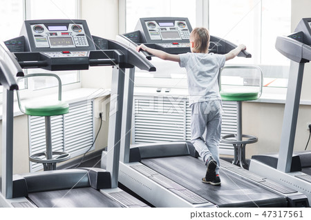 Portrait of a boy on the treadmill in the gym Portrait of a boy on the treadmill in the gym 47317561