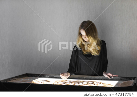 The woman draws on sand, sand animation, sand is pouring from his hands 47317794