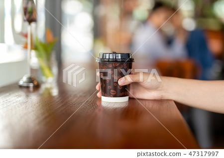 Woman hand holds out a paper cup of coffee to take away. 47317997