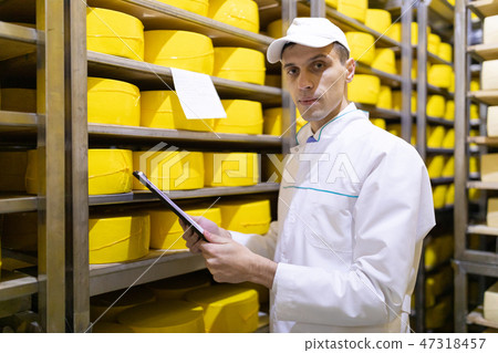 inspector makes notes in the sheet at the cheese warehouse 47318457