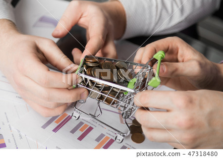 Men's hands pulled in different directions Dummy shopping cart filled with coins Men's hands pulled in different directions Dummy shopping cart filled with coins 47318480