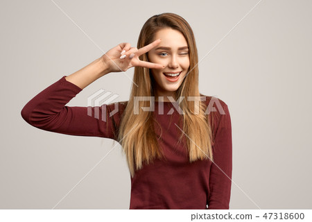 Portrait female showing two fingers and winking Portrait female showing two fingers and winking 47318600