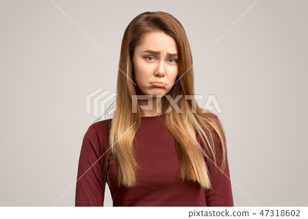 Unhappy woman sulks from sadness, purses lower lip Unhappy woman sulks from sadness, purses lower lip 47318602